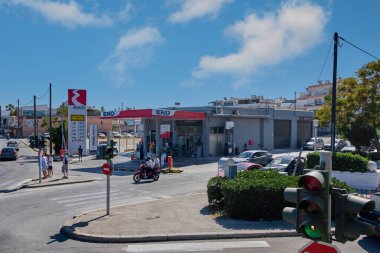 Rodos. Yunanistan - Haziran 06, 2025: Rodos 'ta yoğun bir caddede yakıt ikmali yapan otomobilleri ve motosikletleri olan bir EKO benzin istasyonu. Görüntü günlük hayatı ve şehir hareketini yakalıyor..