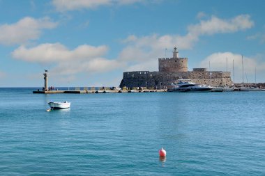Rodas.Yunanistan - Haziran 04, 2025: Mandraki Limanı 'nın panoramik manzarası, tarihi Aziz Nicholas Kalesi, deniz feneri ve berrak mavi suları sergilenmektedir..