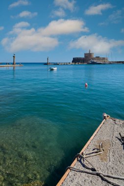 Mandraki Limanı 'nın panoramik manzarası, tarihi Aziz Nicholas Kalesi, uzak deniz fenerleri ve kristal berrak suları sergileniyor..