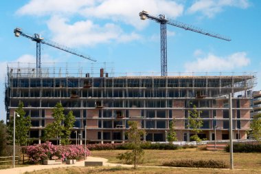 Yeşillik ön planda bitki örtüsü ve etkin bina ile Viladecanlar 'da yeni bir konut veya ticari kompleksin panoramik görünümü.