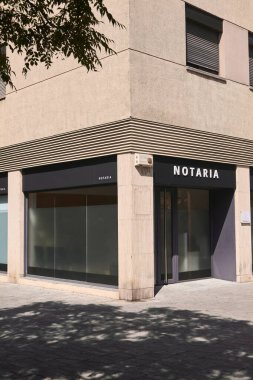 Cam pencereli ve modern mimarisi olan bir köşedeki noter ofisi. Profesyonel binanın ön cephesi, sessiz kentsel sokağı yansıtan büyük cam panellerle koyu koyu bir renktir..