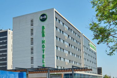 Viladecanlar. Barcelona - 29 Ağustos 2025: B B Oteli 'nin köşesinin alçak açılı görüntüsü, tuğla cephesinin dokusunu ve tabelalarını vurguluyor..