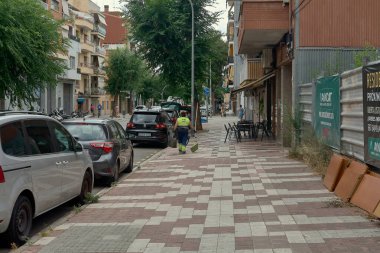 Viladecanlar. Barselona - 2 Eylül 2025: Temizlik işçisi, şehir hizmetlerini ve bir şehri temiz ve düzenli tutmak için gereken günlük işleri temsil eden bir kaldırımı süpürüyor..