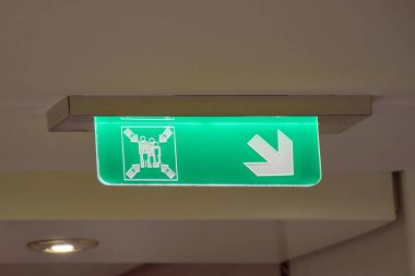 Yakılmış yeşil güvenlik işareti toplanma istasyonunun yönünü gösteriyor. Yolcu tahliyesi için standart bir IMO denizcilik sembolü.