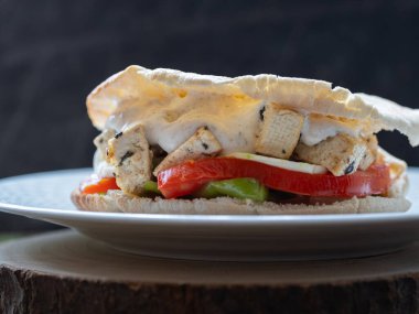 Kızarmış sebze, tofu ve yoğurt soslu vejetaryen sandviçin yakın çekimi. siyah arkaplan