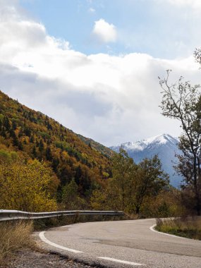 Sonbahar renklerinde ağaçlarla çevrili dağ yolunun kıvrımları. Evet.