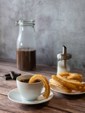 Churro 'lu sıcak çikolatanın dikey fotoğrafı. Çikolata kabının içindeki Churro. 