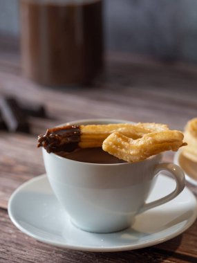 Çikolata kaplı churro 'nun üstüne beyaz bir fincan sıcak çikolata.