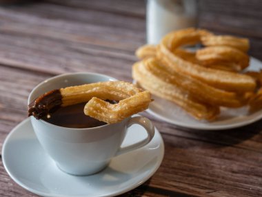 Churros tabağının yanındaki sıcak çikolata bardağına yakın plan. 