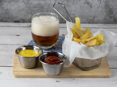 Yanında soğuk bira ve hardallı ve ketçaplı kızartma aperatifi.