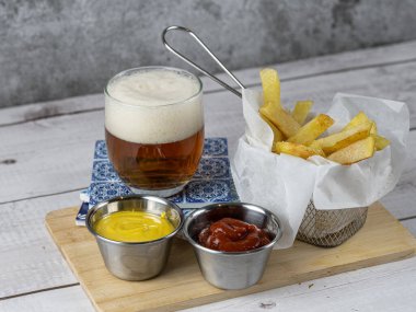 Yanında soğuk bira ve hardallı ve ketçaplı kızartma aperatifi.