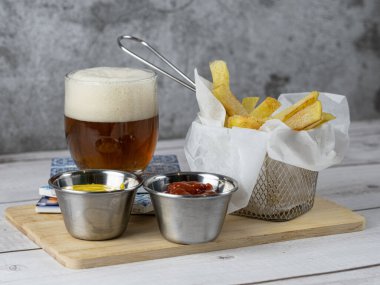 Yanında soğuk bira ve hardallı ve ketçaplı kızartma aperatifi.