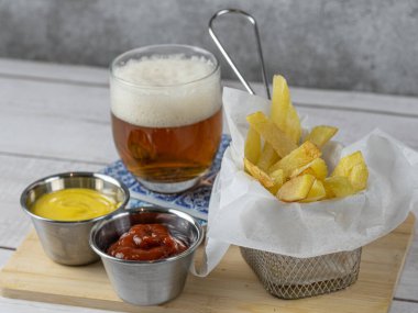 Yanında soğuk bira ve hardallı ve ketçaplı kızartma aperatifi.