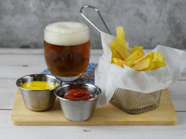 Yanında soğuk bira ve hardallı ve ketçaplı kızartma aperatifi.