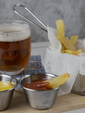 Yanında soğuk bira ve hardallı ve ketçaplı kızartma aperatifi.