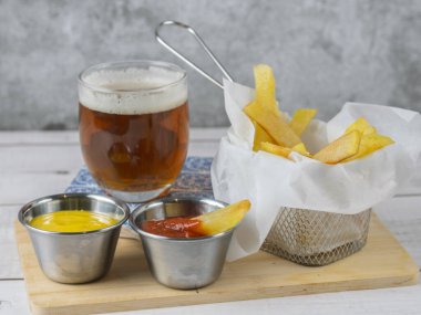 Yanında soğuk bira ve hardallı ve ketçaplı kızartma aperatifi.