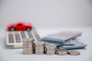Araba sigortası işi, tasarruf satışı, yeni araba için vergi ve kredi. Arka planda bozuk para yığını olan oyuncak araba. Ulaşım finansmanını yönetmeyi planlıyorum. Araba için kredi