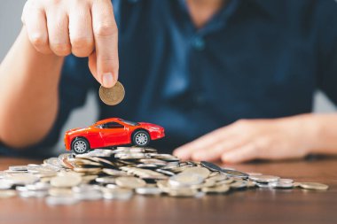 Araba sigortası işi, tasarruf satışı, yeni araba için vergi ve kredi. Arka planda bozuk para yığını olan oyuncak araba. Ulaşım finansmanını yönetmeyi planlıyorum. Araba için kredi