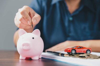 Araba sigortası işi, tasarruf satışı, yeni araba için vergi ve kredi. Arka planda bozuk para yığını olan oyuncak araba. Ulaşım finansmanını yönetmeyi planlıyorum. Araba için kredi