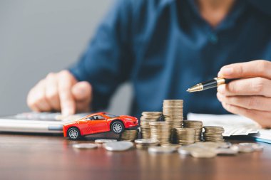 Araba sigortası işi, tasarruf satışı, yeni araba için vergi ve kredi. Arka planda bozuk para yığını olan oyuncak araba. Ulaşım finansmanını yönetmeyi planlıyorum. Araba için kredi