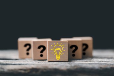 Bilgi ve eğitim kavramı. Yaratıcı fikir ve yenilik kavramı. Elle insan sembolü ve ampul simgesi olan tahta küp bloğu seç. Akıllı teknolojiyle öğreniyor..