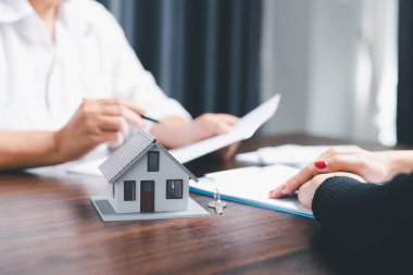 Real estate agents offer contracts to purchase or rent residential. Business person hands holding home model, small building red house. Mortgage property insurance moving home and real estate concept
