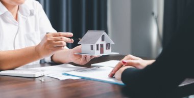 Real estate agents offer contracts to purchase or rent residential. Business person hands holding home model, small building red house. Mortgage property insurance moving home and real estate concept