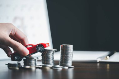 Araba sigortası işi, tasarruf satışı, yeni araba için vergi ve kredi. Arka planda bozuk para yığını olan oyuncak araba. Ulaşım finansmanını yönetmeyi planlıyorum. Araba için kredi
