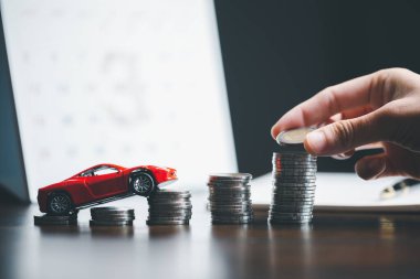 Araba sigortası işi, tasarruf satışı, yeni araba için vergi ve kredi. Arka planda bozuk para yığını olan oyuncak araba. Ulaşım finansmanını yönetmeyi planlıyorum. Araba için kredi
