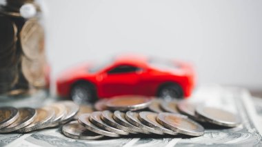 Araba sigortası işi, tasarruf satışı, yeni araba için vergi ve kredi. Arka planda bozuk para yığını olan oyuncak araba. Ulaşım finansmanını yönetmeyi planlıyorum. Araba için kredi