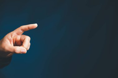 Closeup of businesswoman hand on empty dark blue background in office for design work, insert icon bundle or business technology symbols or other. selective focus on hand. female online working