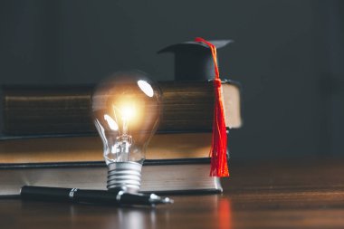 Mezuniyet şapkalı ampuller ve kitaplar. Kitap okuma, bilgi ve yeni fikirler arama kavramı. Yenilik ve ilham. Parlayan ışıklarla yaratıcılık. Fikirlerin ilham kaynağı..