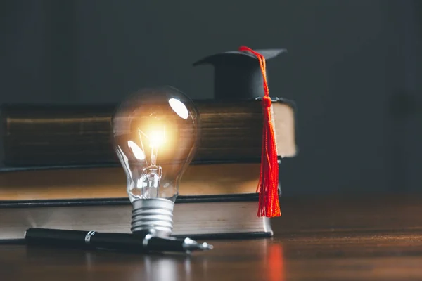 電球や卒業帽子付きの本 本や知識を読み 新しいアイデアを探すというコンセプト 革新とインスピレーション 輝く光で創造性 アイデアのインスピレーション — ストック写真