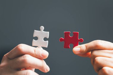 İş kadını, elinde bulmaca parçasıyla strateji ve çözüm önerisi tutuyor. İki yapbozun yakın kısmı birbirine bağlanıyor. İşbirliğine katılma kavramı. Başarılı takım çalışması.