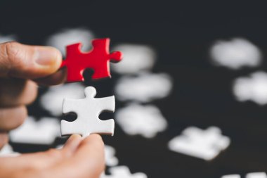İş kadını, elinde bulmaca parçasıyla strateji ve çözüm önerisi tutuyor. İki yapbozun yakın kısmı birbirine bağlanıyor. İşbirliğine katılma kavramı. Başarılı takım çalışması.