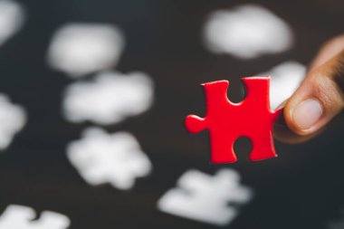 İş kadını, elinde bulmaca parçasıyla strateji ve çözüm önerisi tutuyor. Kırmızı bir yapbozun yakın kısmı birbirine bağlanıyor. İşbirliğine katılma kavramı. Başarılı takım çalışması.