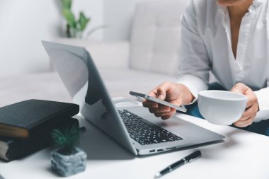 Sosyal medya günü konsepti. Kadın serbest çalışan, akıllı telefonlu bir internet sitesi için oturma odasında çalışmaya başlıyor. Ofiste çalışan bir iş kadını. İnternet teknolojisiyle iletişim kuran kadın.
