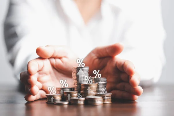 İş kadını eline oklu ve faiz oranı ve mortgage oranlarının yüzde sembolü olan bir tomar para veriyor. Simge yüzdesi sembolü ve yukarı bakan ok.