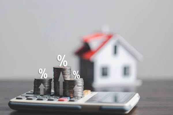 Stacks of coins and model house with percentage symbol for increasing interest rates. Interest rate financial and mortgage rates. Icon percentage symbol and arrow pointing up. Home price or increase.