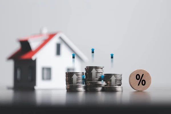 stock image Stacks of coins and model house with percentage symbol for increasing interest rates. Interest rate financial and mortgage rates. Icon percentage symbol and arrow pointing up. Home price or increase.