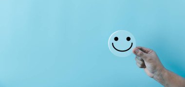 Mavi yuvarlak nesnenin üzerinde el ele tutuşan mutlu yüz gülümseme ikonu. Müşteri tecrübesi ve memnuniyet konseptiyle hizmet. pozitif düşünce, ruh sağlığı değerlendirmesi, dünya ruh sağlığı günü.