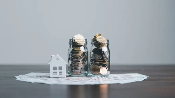 Coins stack with mini house on wooden table, home loan, Save money concept, Property investment, house loan, reverse mortgage, gold coins money stack growth, saving money coins stack future for home.