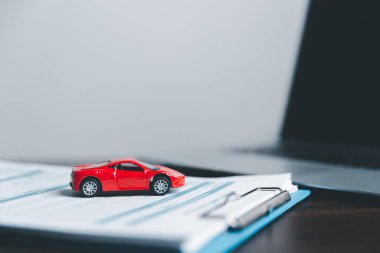 Business woman's hand protecting red toy car on desk. Planning to manage transportation finance costs. Concept of car insurance business, saving buy - sale with tax and loan for new car.