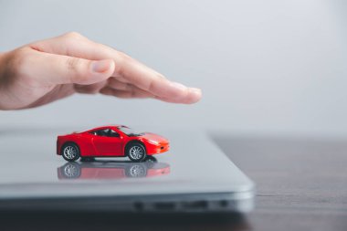 Business woman's hand protecting red toy car on desk. Planning to manage transportation finance costs. Concept of car insurance business, saving buy - sale with tax and loan for new car.