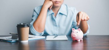 Business asian woman hand put coins in piggy bank on wood table background, saving money wealth and financial concept, finance, investment, Financial planning.Financial planning deposit for retirement