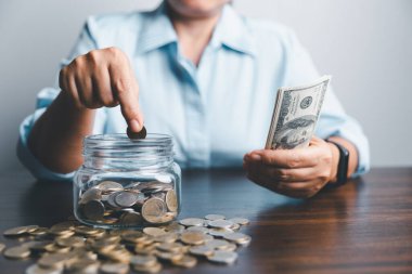 Business asian woman hand put coins in piggy bank on wood table background, saving money wealth and financial concept, finance, investment, Financial planning.Financial planning deposit for retirement