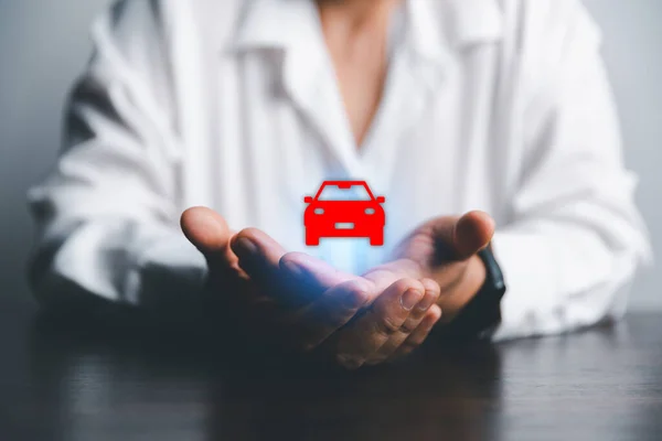 Business woman\'s hand protecting red icon car on desk. Planning to manage transportation finance costs. Concept of car insurance business, saving buy - sale with tax and loan for new car.