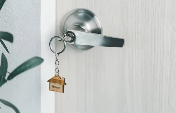 close up key on the door with morning light, personal loan concept. House model and key in house door. Real estate agent offer house, property insurance and security, affordable housing concepts.