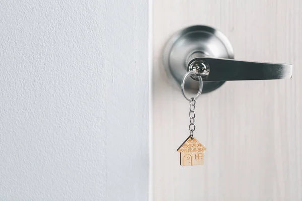 close up key on the door with morning light, personal loan concept. House model and key in house door. Real estate agent offer house, property insurance and security, affordable housing concepts.