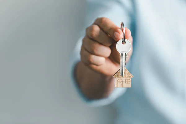 key to your own home in the palm of the girl and a wooden for real estate renting property. House model and key in house door. Real estate agent offer house, property insurance.